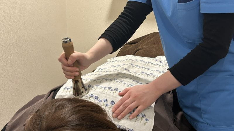背中を温灸器で温めます